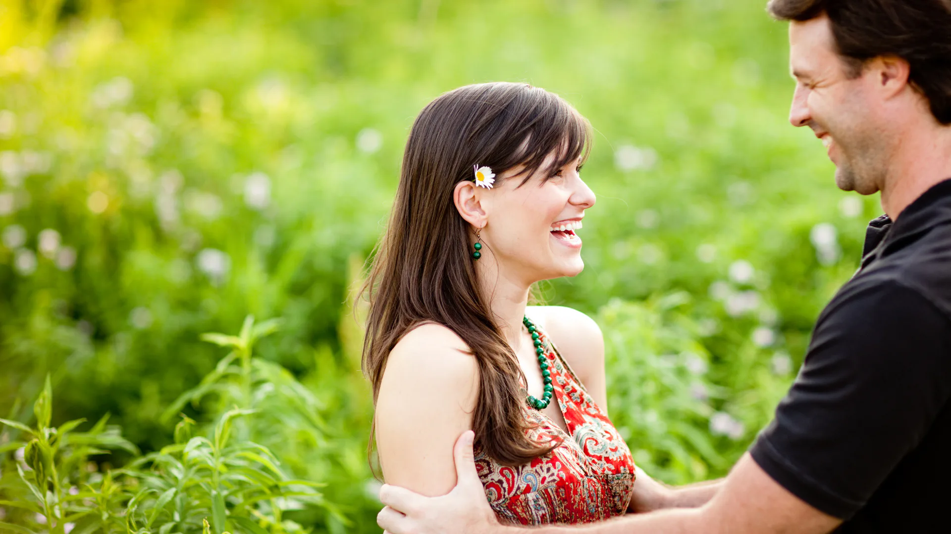 A happy couple smiling outdoors in a green field, representing joy, connection, and appreciation of small moments.
