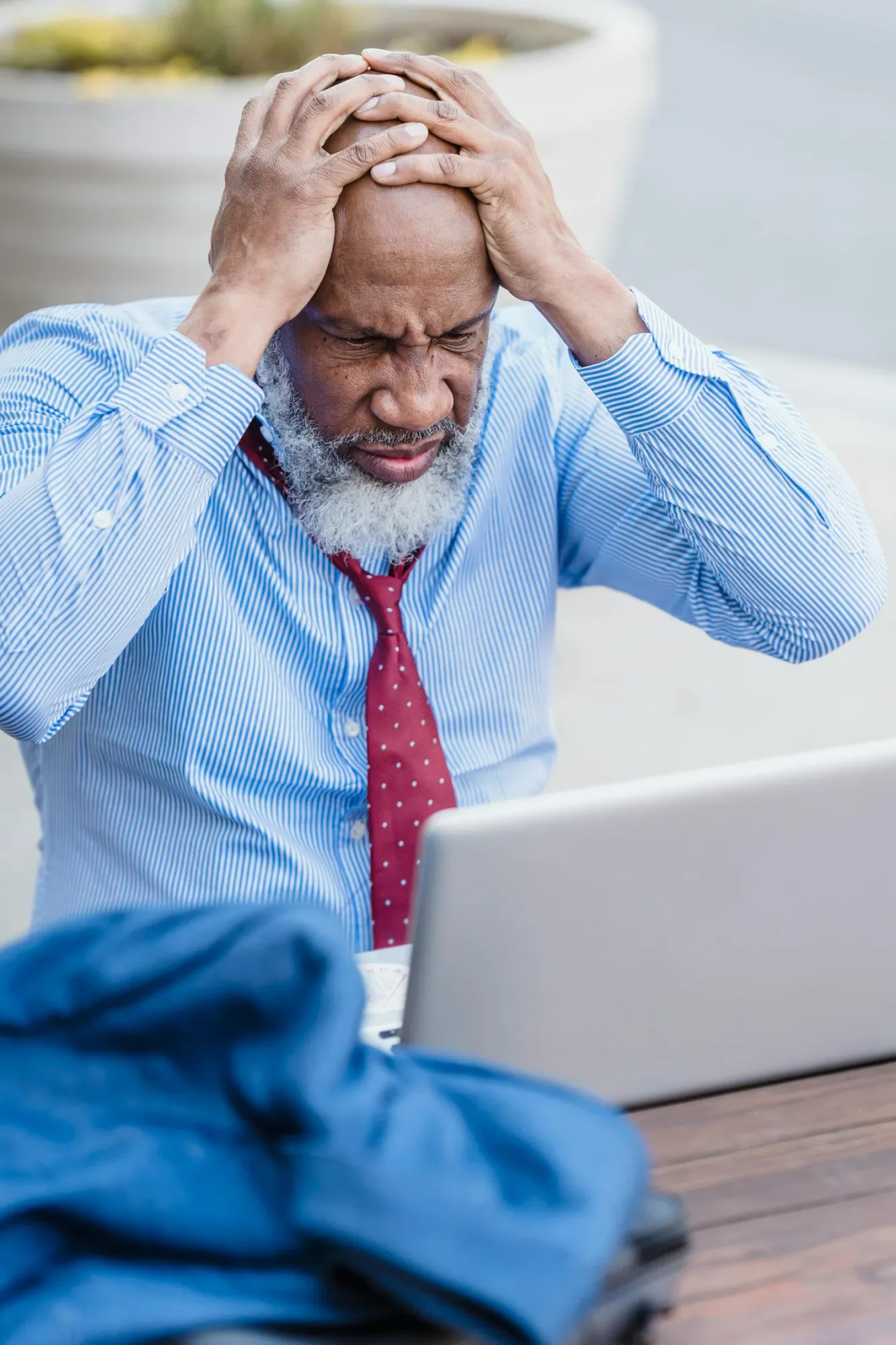Stressed man holding his head at a laptop, illustrating burnout, anxiety, and the value of a caring birthday message