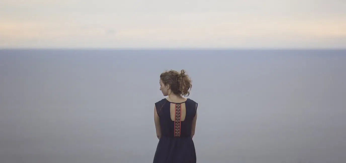 Woman standing alone before a calm horizon, symbolizing emotional reflection, self-awareness, and connection in relationships.